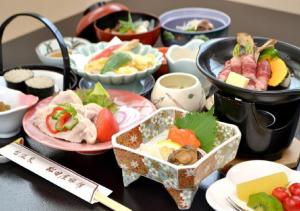 Dai Onsen Matsudaya Ryokan - Vacation STAY 67499 في هاناماكي: طاولة مليئة بأطباق الطعام على طاولة
