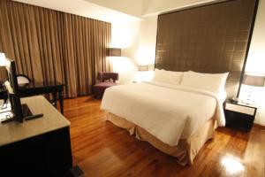 ein Hotelzimmer mit einem großen Bett und einem Schreibtisch in der Unterkunft Hotel Diradja in Jakarta