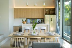a dining room with a table and chairs and a kitchen at Himmapana Villas - Terraces - SHA Extra Plus in Kamala Beach