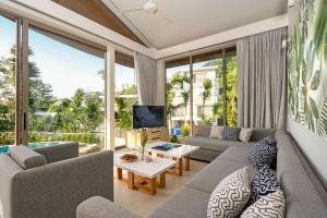 a living room with a couch and a tv at Himmapana Villas - Terraces - SHA Extra Plus in Kamala Beach