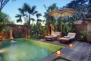 una piscina con 2 sillas y una sombrilla en PAWANA VILLAS, en Ubud