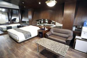 1 dormitorio con cama, sofá y mesa en Lex Suwa (Adult Only), en Suwa