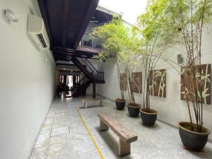 a hallway with potted trees and a wooden bench at Heeren Straits Hotel in Malacca