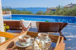 two cups of coffee on a table next to a pool at House Arija in Makarska