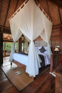 Schlafzimmer mit einem Bett mit Moskitonetz in der Unterkunft PAWANA VILLAS in Ubud
