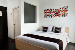 a bedroom with a large bed and a painting on the wall at Tuju Abuserin Syariah in Jakarta