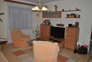 a living room with a television and a couch and chairs at Anett Apartman in Siófok