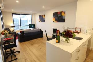 a kitchen and living room with a couch and a table at Melbourne Knox Central Apartment Hotel Official in Wantirna