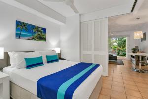 道格拉斯港Port Douglas Apartments - Adults Only Oasis的一间带大床的卧室和一间客厅