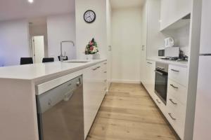 a kitchen with white counters and a clock on the wall at Melbourne Knox Central Apartment Hotel Official in Wantirna