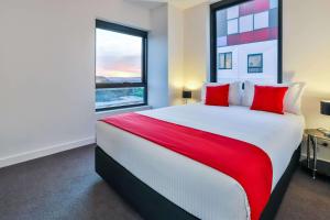 a bedroom with a large bed with red pillows at Melbourne Knox Central Apartment Hotel Official in Wantirna
