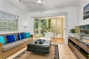 a living room with a couch and a tv at Port Douglas Apartments in Port Douglas