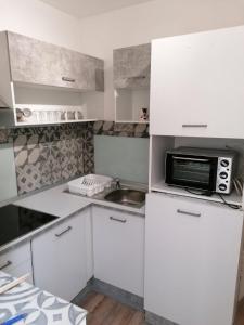 een kleine keuken met witte kasten en een magnetron bij Apartment Ida in Piran