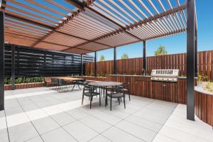 a patio with a wooden pergola and tables and chairs at Sky One Apartments by CLLIX in Box Hill