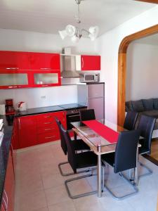 uma cozinha com armários vermelhos, uma mesa e cadeiras em Rafa´s house em Selca