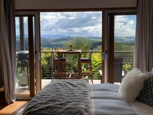 班加洛Callemondah Studio with stunning views, in Bangalow and Byron Hinterland的一间带床的卧室和一个可欣赏美景的阳台