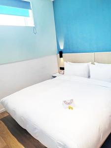 Una gran cama blanca en una habitación con una pared azul. en PACE HOTEL Suzhou Renmin Branch en Suzhou