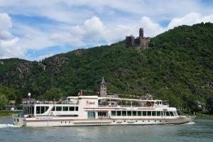 a boat on the water with a castle in the background at 4-Sterne Ferienwohnung Carbach -Perfekt für Radfahrer- in Boppard