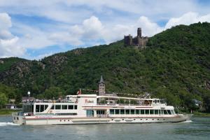 ein Boot auf dem Wasser mit einem Schloss im Hintergrund in der Unterkunft 4-Sterne Ferienwohnung Carbach -Perfekt für Radfahrer- in Boppard