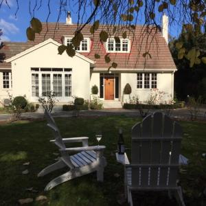 a white house with a chair and a bottle of wine at number41 Bed + Breakfast in Blenheim