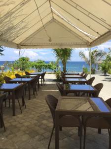 uma fila de mesas e cadeiras com o oceano ao fundo em EM Royalle Hotel & Beach Resort em San Juan