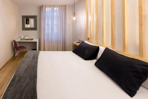 a bedroom with a large white bed with black pillows at Hotel Fruela in Oviedo