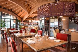 モンテカルロにあるBuonamico Wine Resortの木製のテーブルと椅子、シャンデリアのあるレストラン