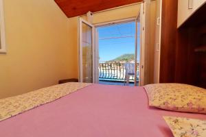 a bedroom with a pink bed and a balcony at Apartments Peselj in Smokvica +40 photos
