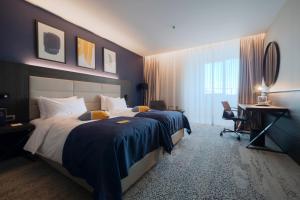 een hotelkamer met een groot bed en een bureau bij voco - Podgorica, an IHG Hotel in Podgorica