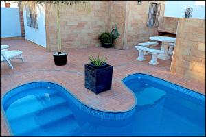 a swimming pool in a patio with a table and a bench at Chalet 2 dormitorios con piscina privada in Conil de la Frontera