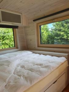 a bed in a small room with two windows at Tiny House Steirerbua in Birkfeld