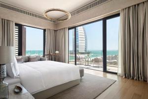 a bedroom with a large white bed and large windows at Jumeirah Al Naseem Dubai in Dubai