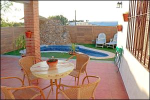 une terrasse avec une table, des chaises et une piscine dans l'établissement Chalet acogedor con piscina, à Conil de la Frontera