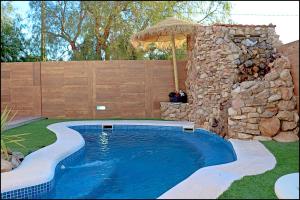 - une piscine dans une cour dotée d'un mur en pierre dans l'établissement Chalet acogedor con piscina, à Conil de la Frontera