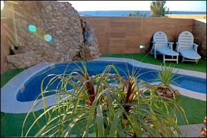 un jardin avec deux chaises et une piscine dans l'établissement Chalet acogedor con piscina, à Conil de la Frontera