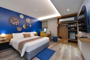 1 dormitorio con 1 cama grande y pared azul en Aspira One Sutthisan en Bangkok