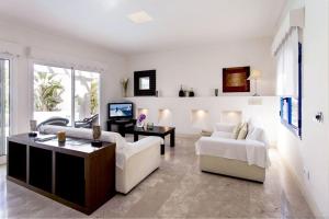 Una sala de estar con muebles blancos y una gran ventana. en Villa Alegria, en La Oliva