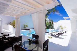 Un patio con sillas y una mesa y una piscina. en Villa Alegria, en La Oliva