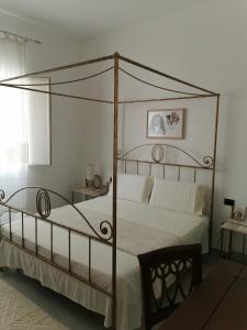 1 dormitorio con cama con dosel y almohadas blancas en Affittacamere Alisso, en Olbia