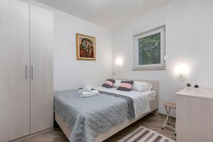 a white bedroom with a bed and a window at House Bumbiste 1703 in Banjole