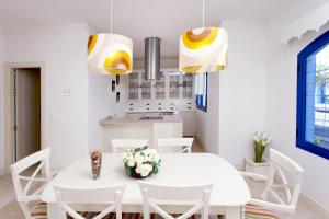 Un comedor blanco con una mesa y sillas blancas. en Villa Alegria, en La Oliva