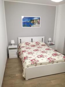 Un dormitorio blanco con una cama con flores. en Casa vacanze Fabrizio, en Andrano