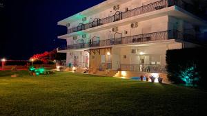 un gran edificio blanco con luces en un patio por la noche en Maritsa's Rooms, en Stavros