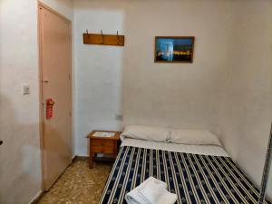 Habitación pequeña con cama y mesita de noche en AB Pension Granada, en Granada