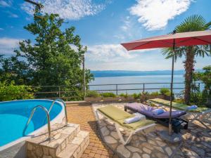 eine Terrasse mit einem Sonnenschirm und Stühlen sowie einem Pool in der Unterkunft Holiday Home Villa More by Interhome in Lovran