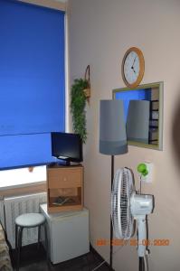 a room with a fan and a desk with a television and a clock at гостевой Дом БельвеДеръ in Vyborg