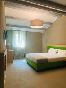 a bedroom with a bed with a green headboard at Hotel Conca D'Oro ***S in Garda