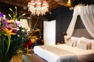 a bedroom with a bed and a chandelier and flowers at Boutique Hotel De Castillion - Small elegant family hotel in Bruges