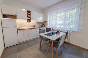 una cocina con armarios blancos y una mesa con sillas. en Apartman Danube lux, en Novi Sad