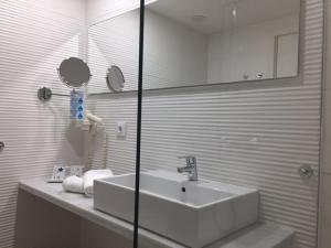 La salle de bains blanche est pourvue d'un lavabo et d'un miroir. dans l'établissement Oleander, à Playa de Palma